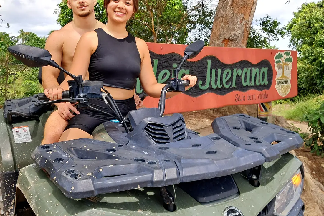 Casal no quadriciclo ao lado da placa da aldeia Juerana