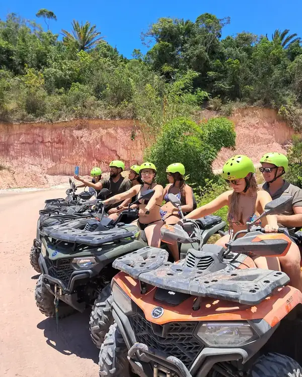 Grupo de capacete nos quadriciclos em frente à falésia