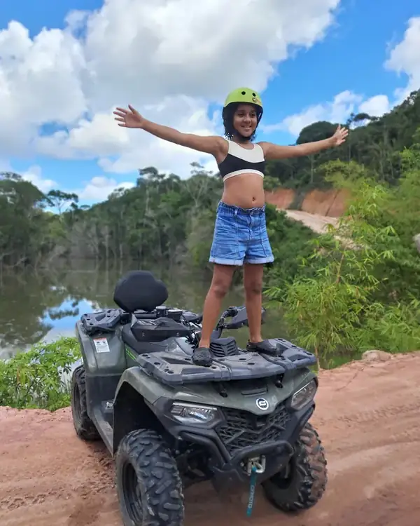 Criança de braços abertos no quadriciclo