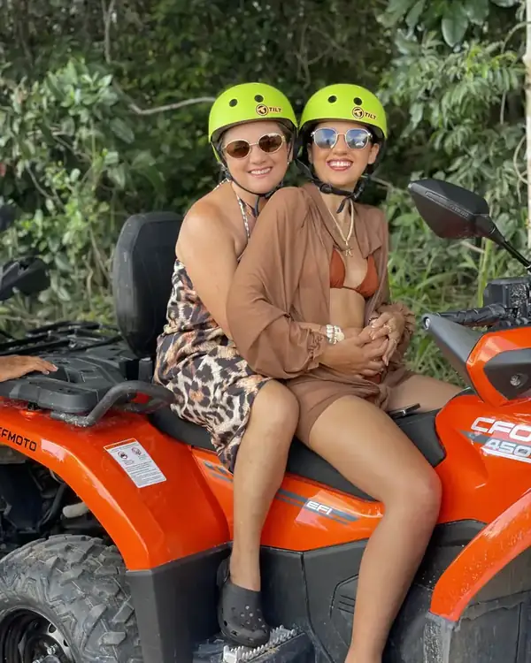 Duas amigas de capacete no quadriciclo laranja