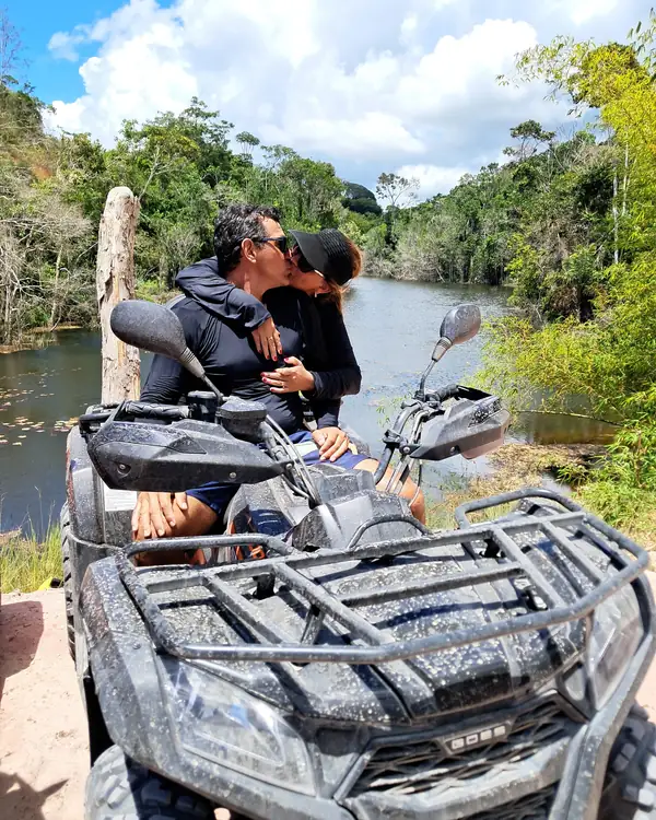 Casal no quadriciclo à beira do rio