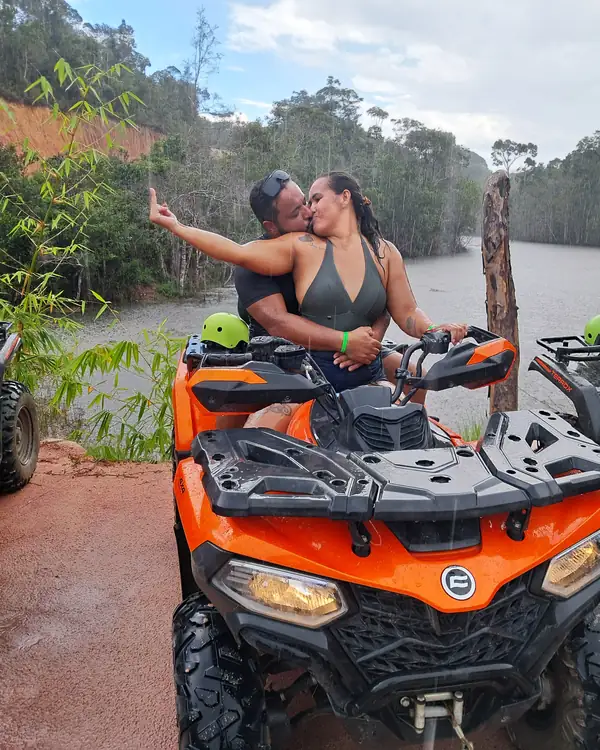Casal no quadriciclo laranja à beira do rio