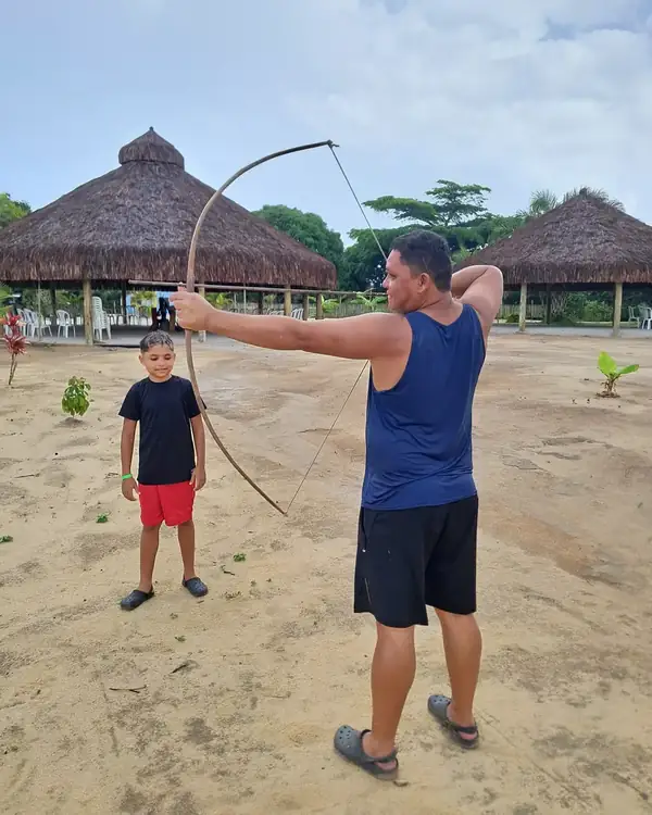 Visitantes praticando arco e flecha na aldeia Pataxó